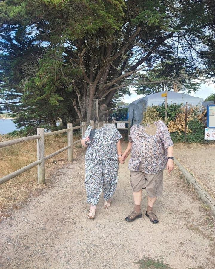 Deux personnes marchant main dans la main sur un sentier du littoral